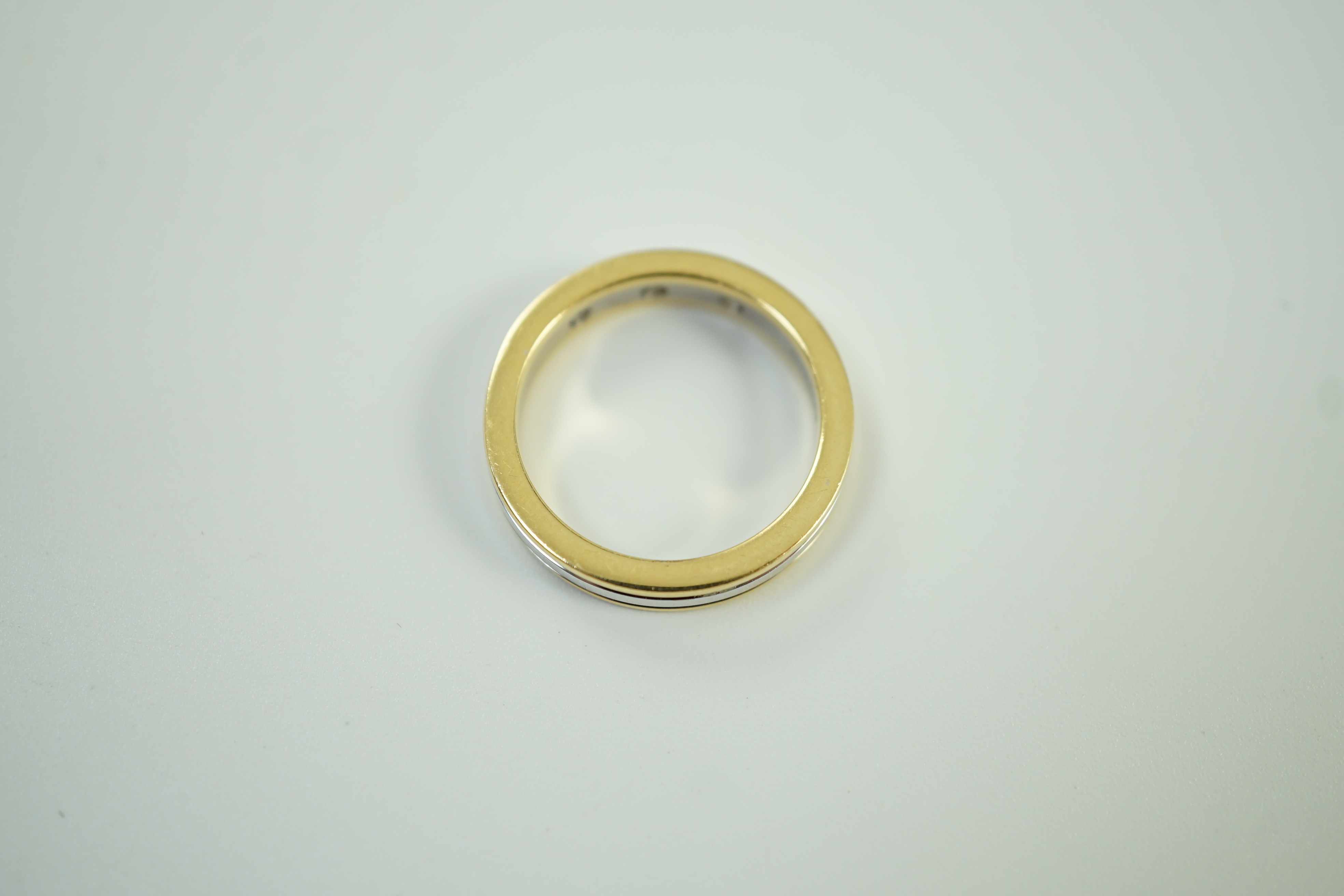 A modern Simbol two colour 18ct gold and gypsy set three stone diamond band, size M, gross weight 6.7 grams.